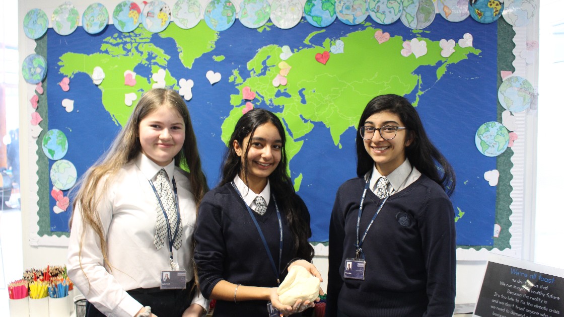 Three students smiling and holding dough
