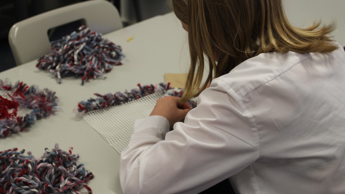 Student working on a latch hook cushion project
