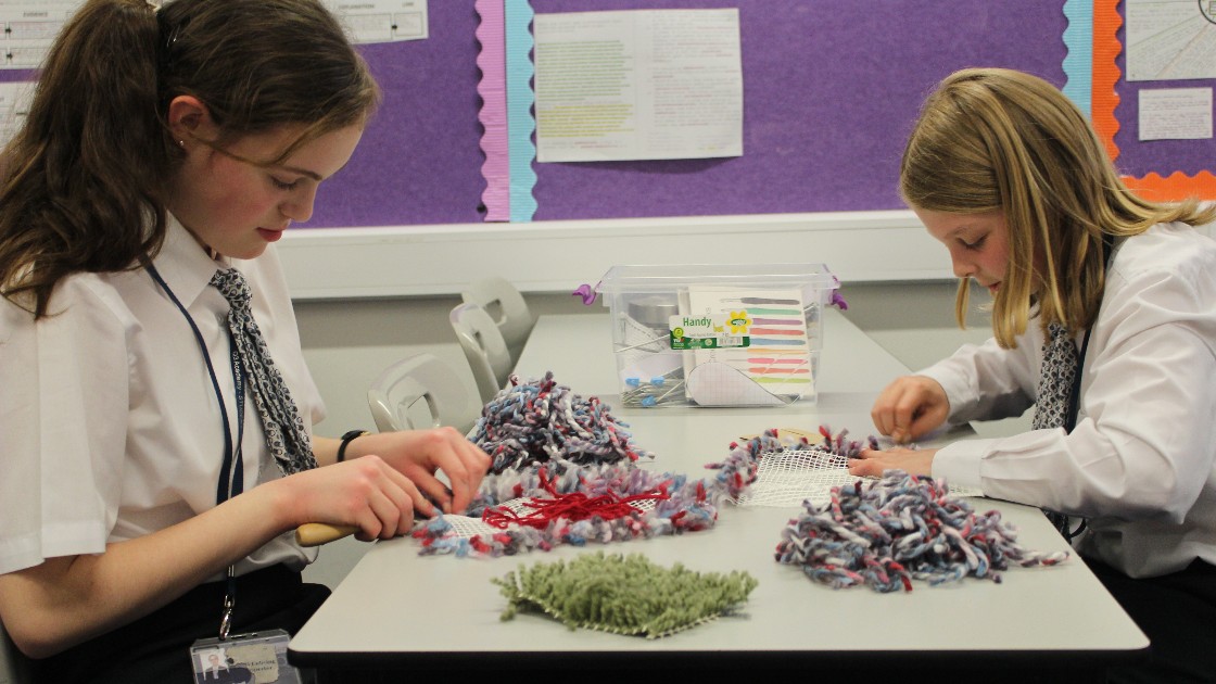 Two students working on their latch rug designs