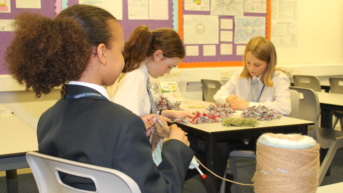 Students working on knitting and latch hook canvas