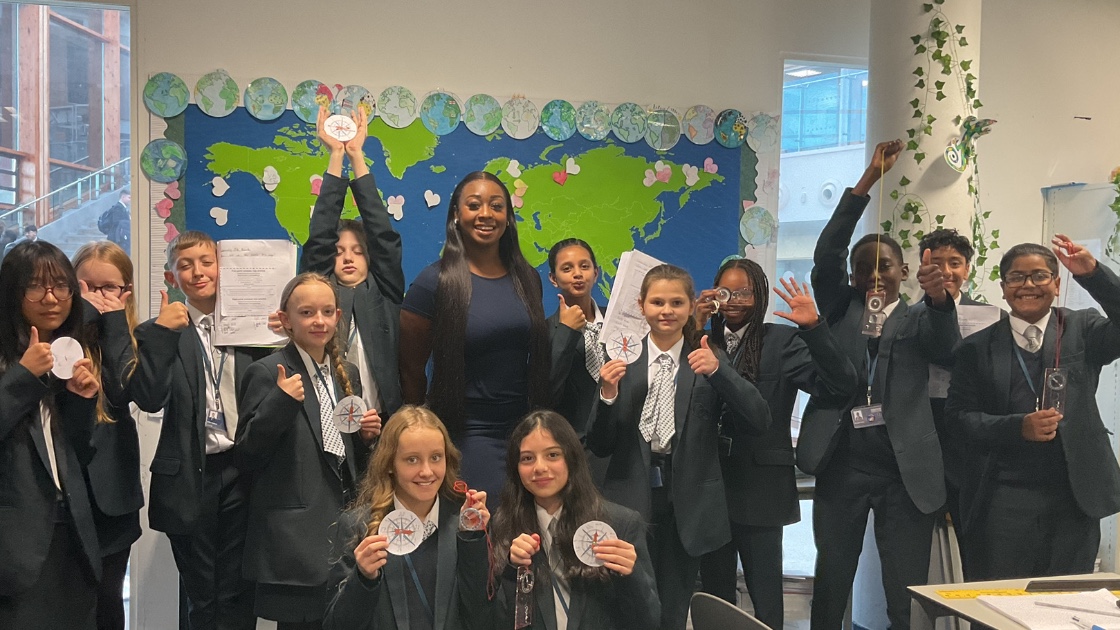 Children holding up compasses and smiling