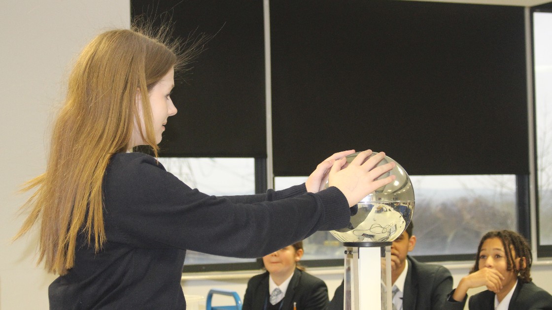 A student placing their hands on a Van de Graaff.
