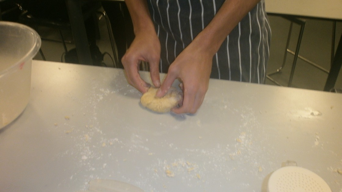 Student kneading pasta dough.