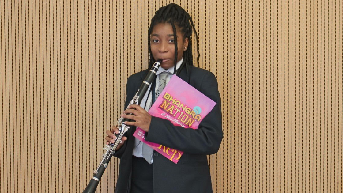 A student poses with their clarinet and the programme.