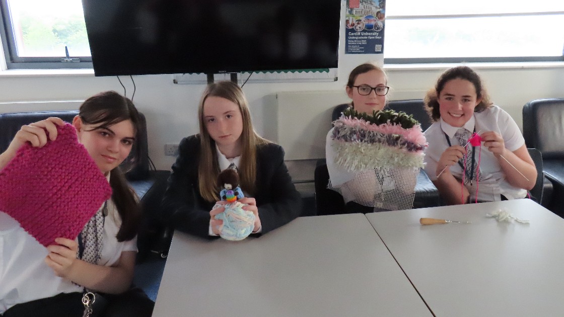 Four students displaying their knitting and latching work