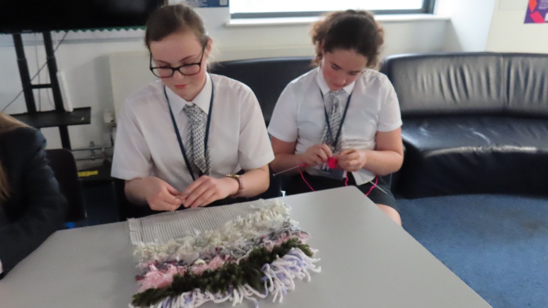 Two students sat working on latching and knitting projects