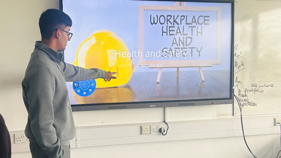 Student presenting a slide on workplace health and safety in a classroom