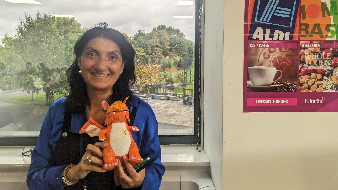 Teacher holding a dragon toy in a classroom