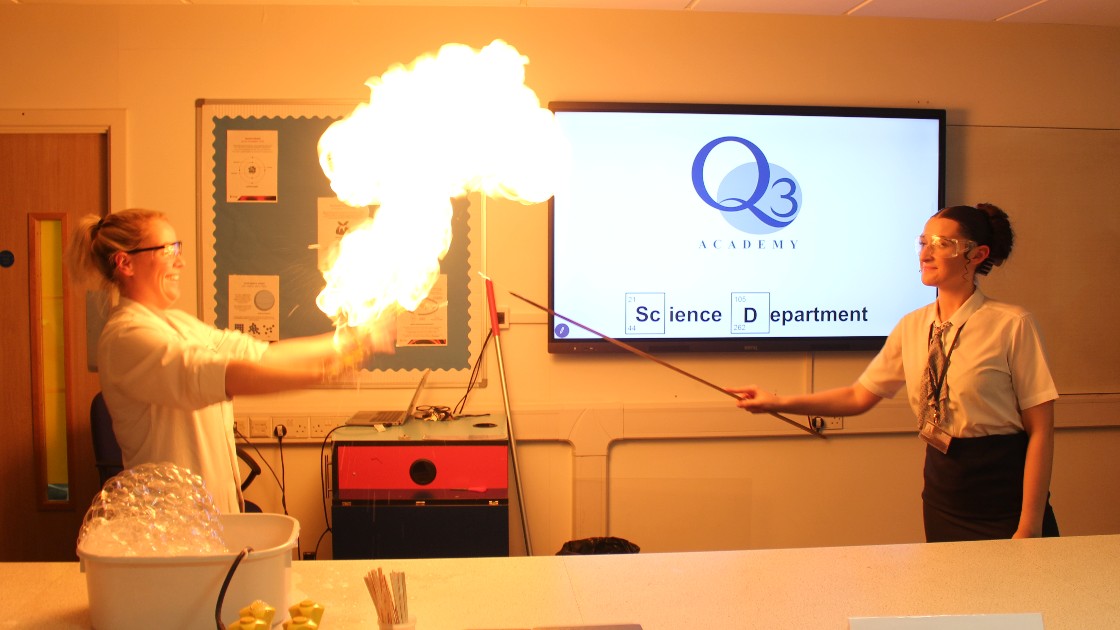 Two teachers conducting a science experiment with fire in a classroom