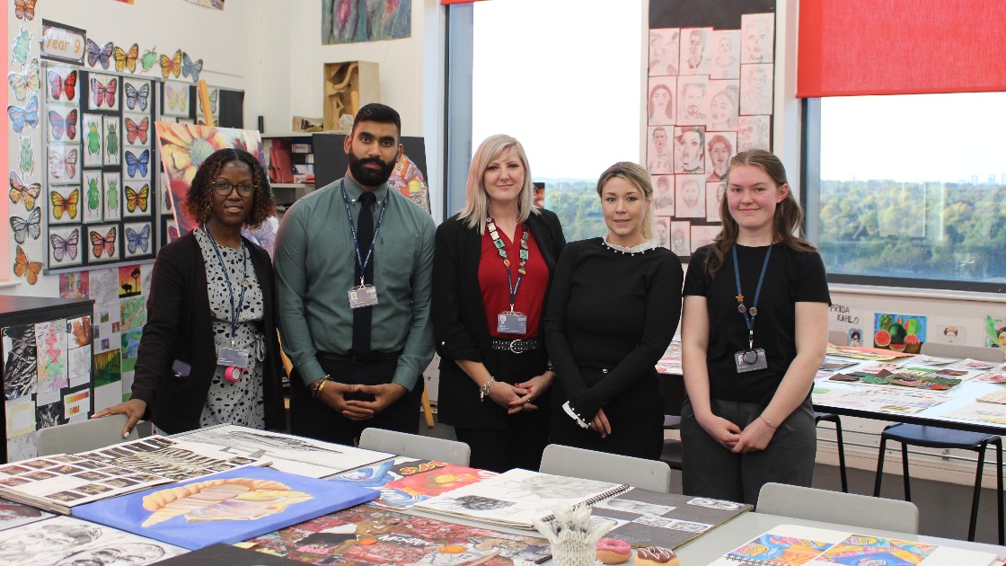 Teachers standing in an art classroom with student artwork displayed on tables and walls