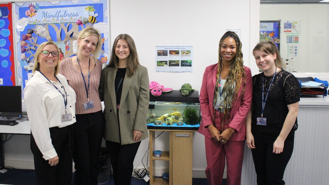 Group of staff standing in a classroom with a fish tank