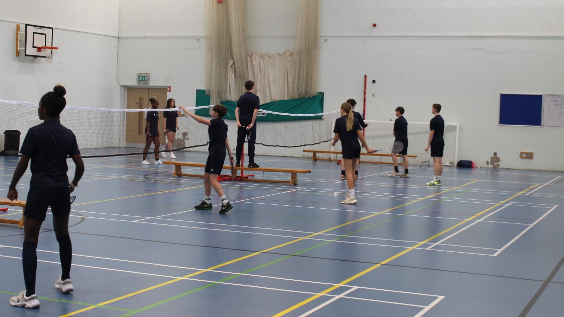 Students playing badminton in a sportshall.