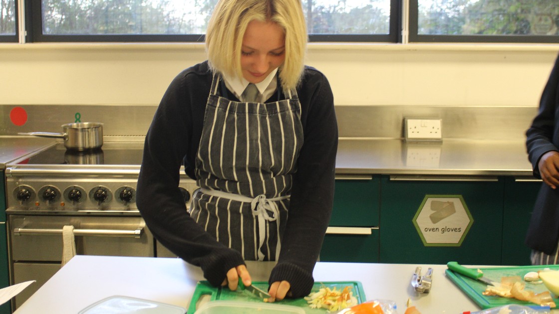 Student chopping vegetables in a kitchen