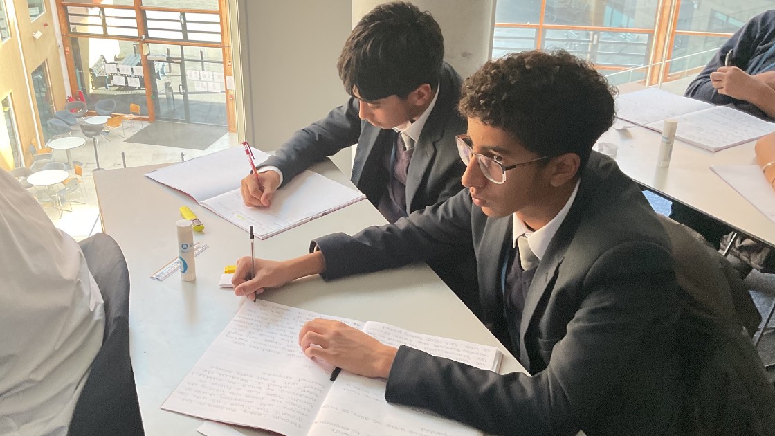 Students in a classroom writing in notebooks