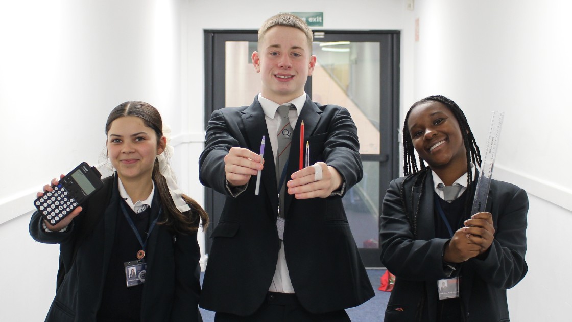 Three students holding a calculator, pens, and a ruler
