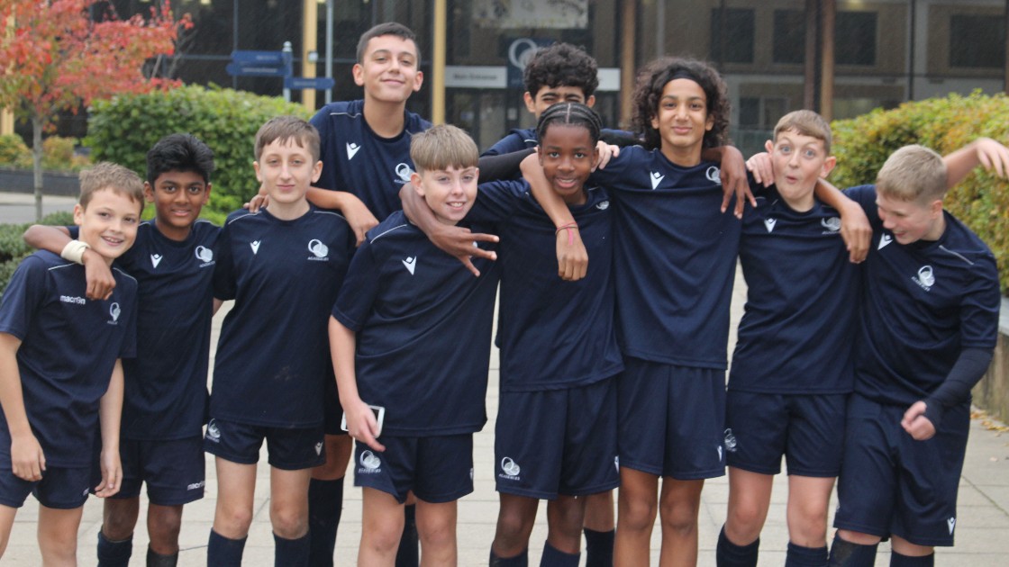 Group of Year 8 boys in football kits posing together outdoors