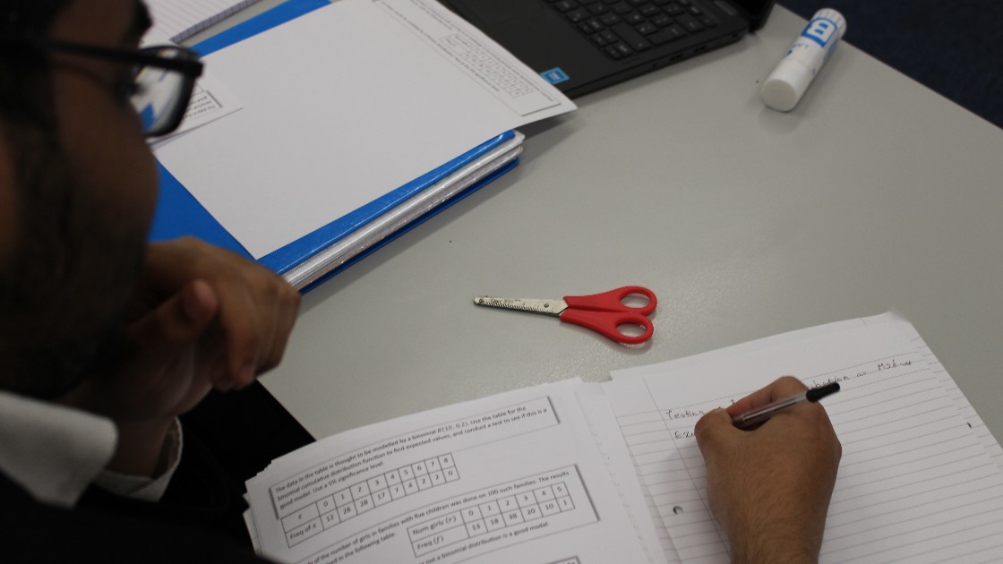A student writing in a notebook during a maths lesson