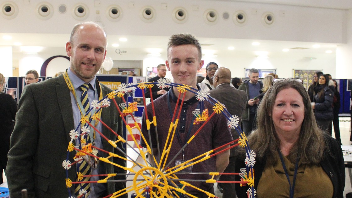 A student and two teachers standing behind a Ferris wheel model