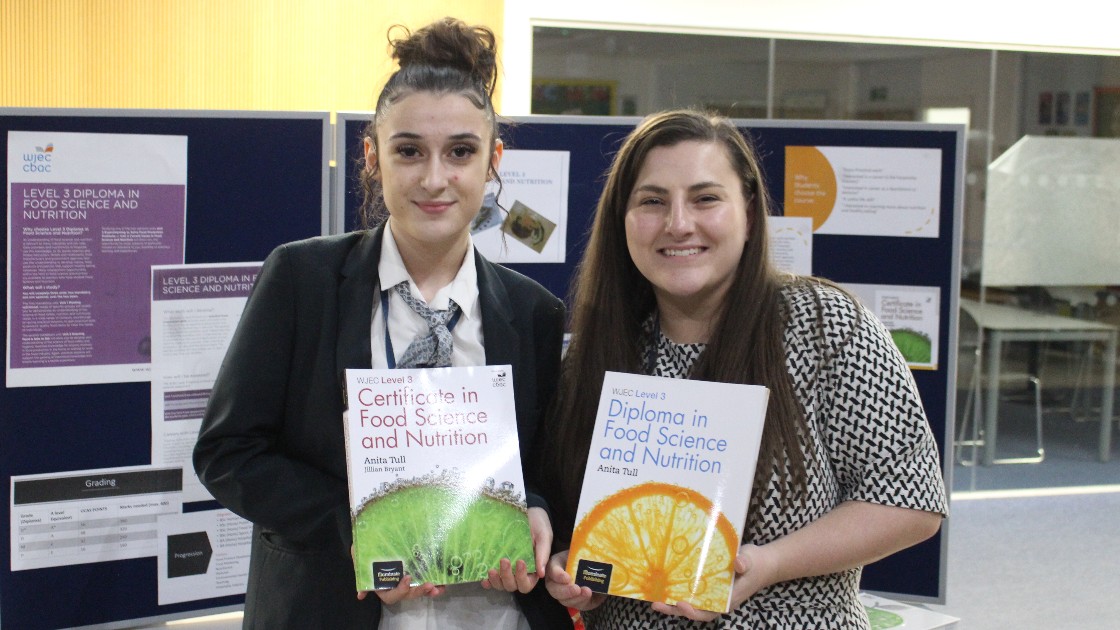A student and a teacher holding books on food science and nutrition