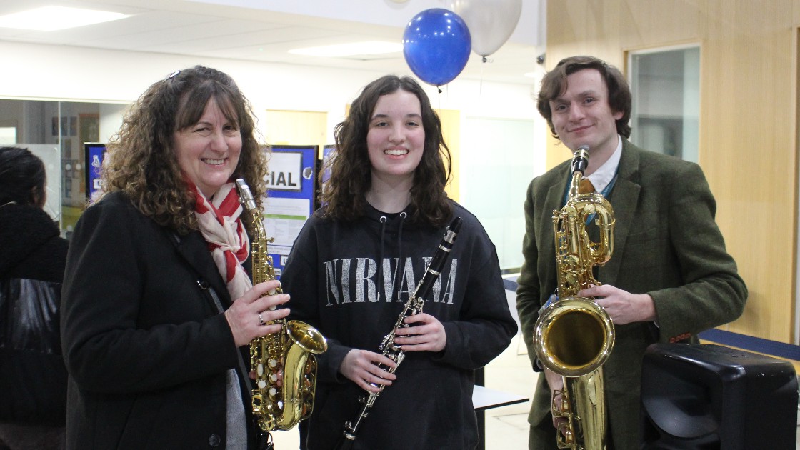 A parent, student, and teacher holding musical instruments