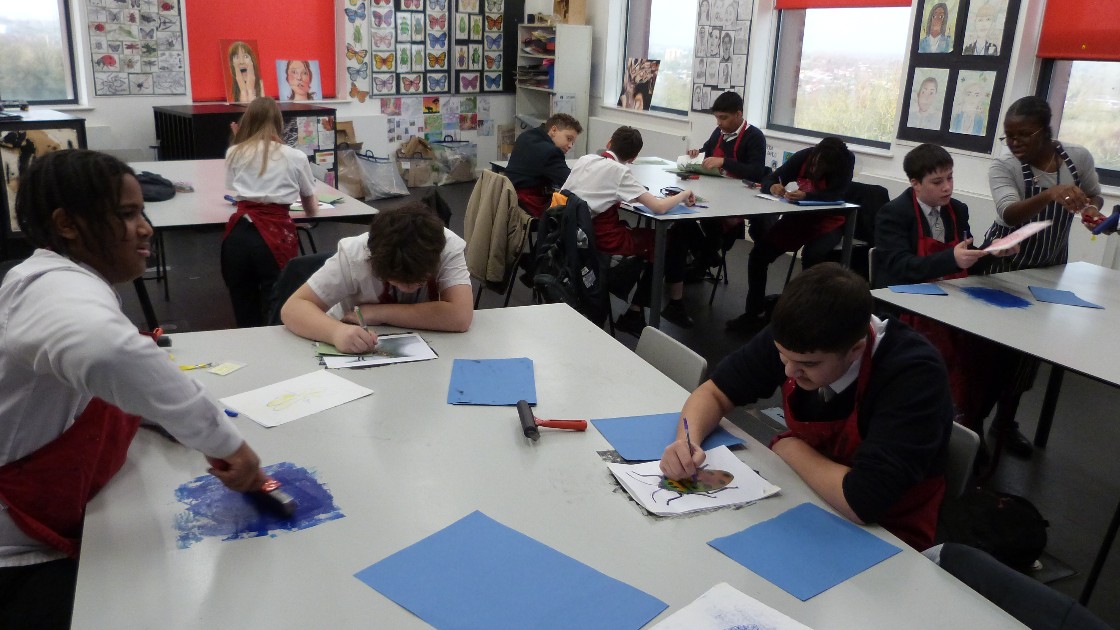 Students in an art classroom working on various art projects, with a teacher assisting