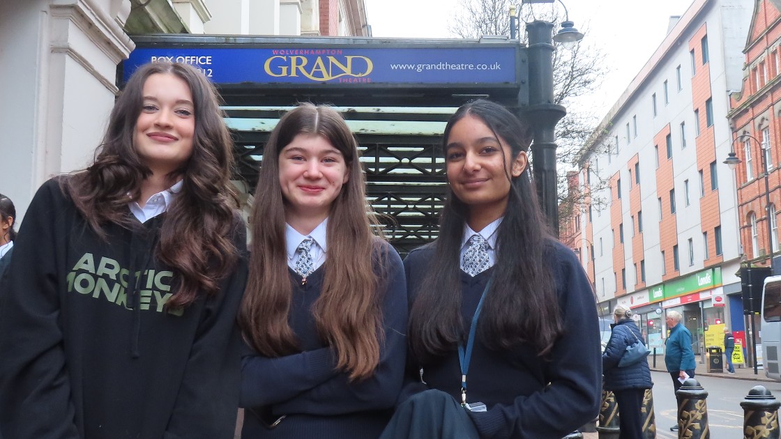 Three students in school uniforms standing outside the Grand Theatre