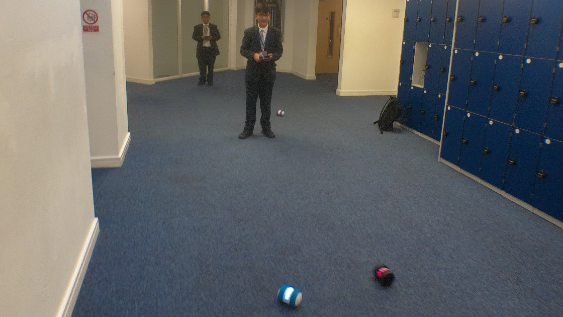 A student controlling small robotic devices in a school hallway
