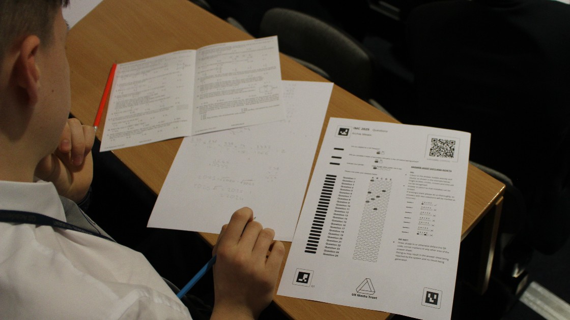 A student working on a maths challenge paper at a desk