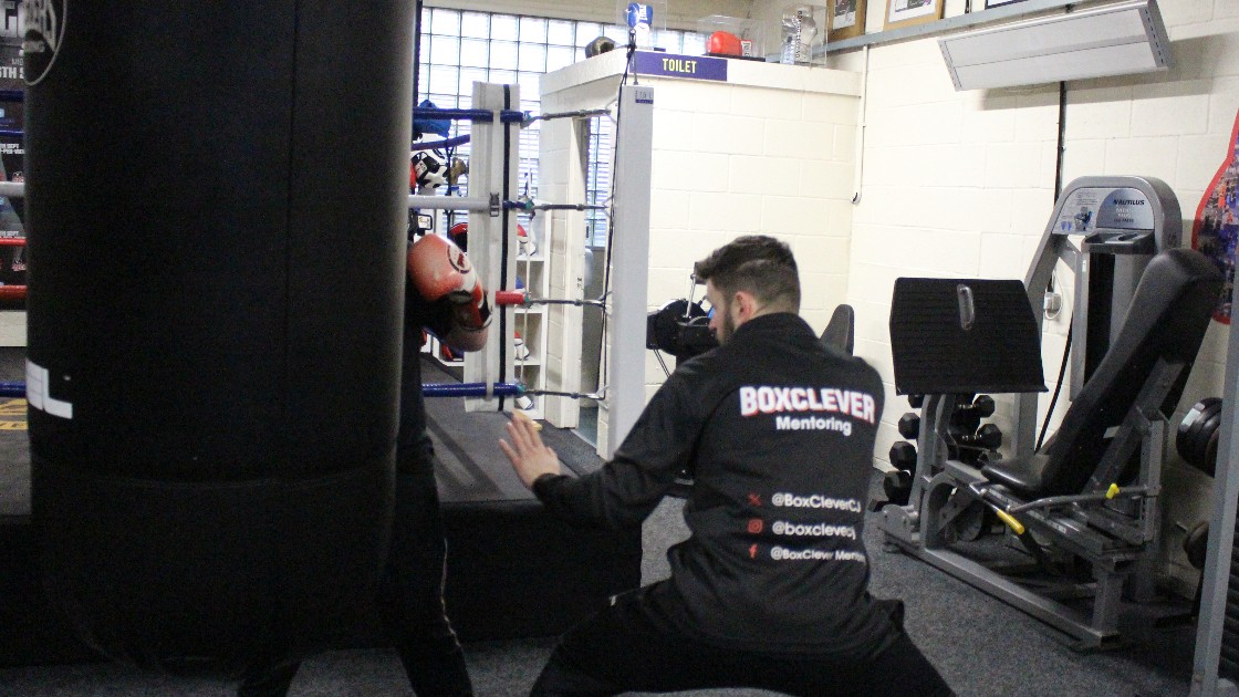 A mentor and a student practising boxing techniques in a gym