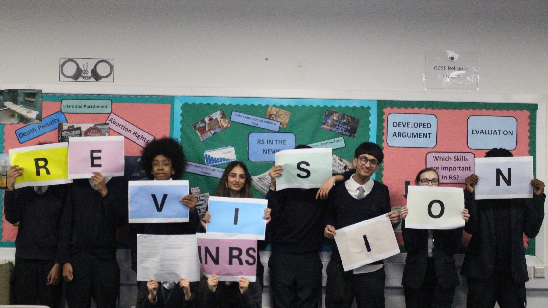 Students holding colourful signs spelling 'REVISION' in an RS classroom