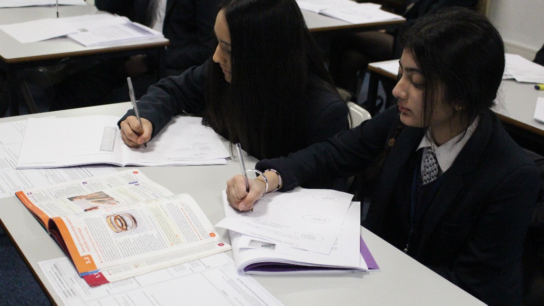Two students in a classroom working on Religious Studies assignments