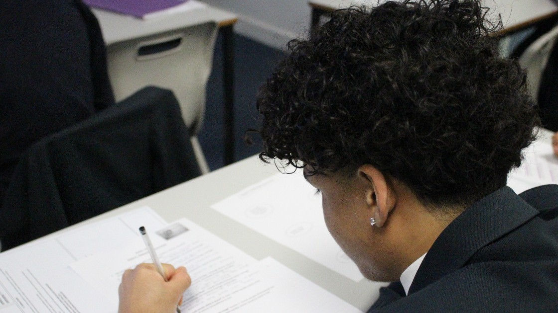 A student writing on a worksheet during an RS lesson
