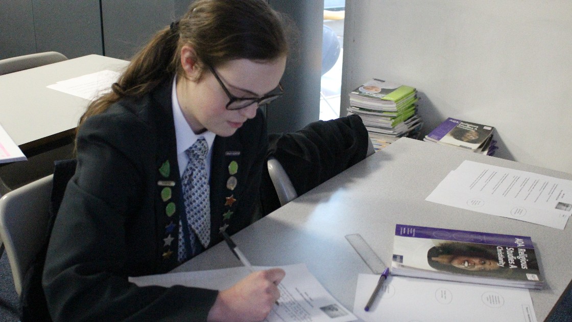 A student in a school uniform working on a worksheet at a desk