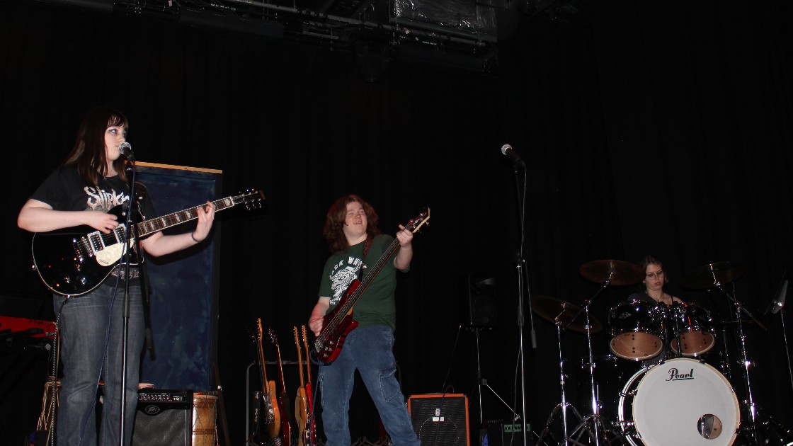Students performing on stage with guitars and drums during a Battle of the Bands event