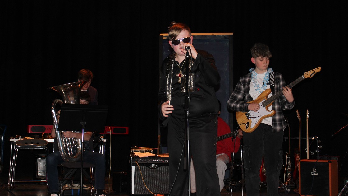 Students performing on stage with musical instruments during Battle of the Bands