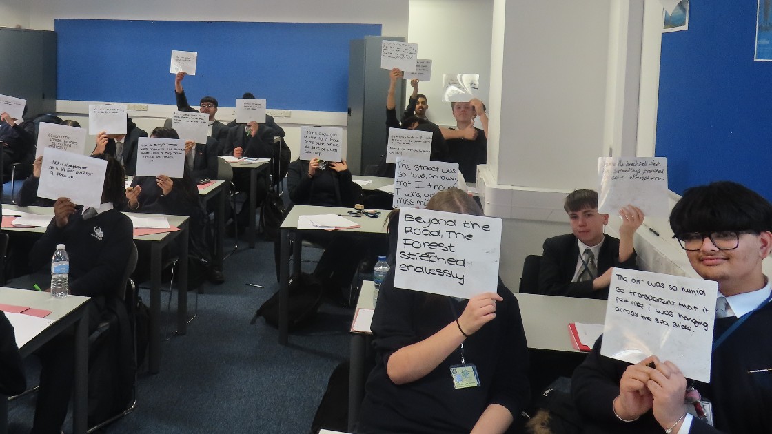 Students in a classroom holding up whiteboards with written sentences during an English lesson