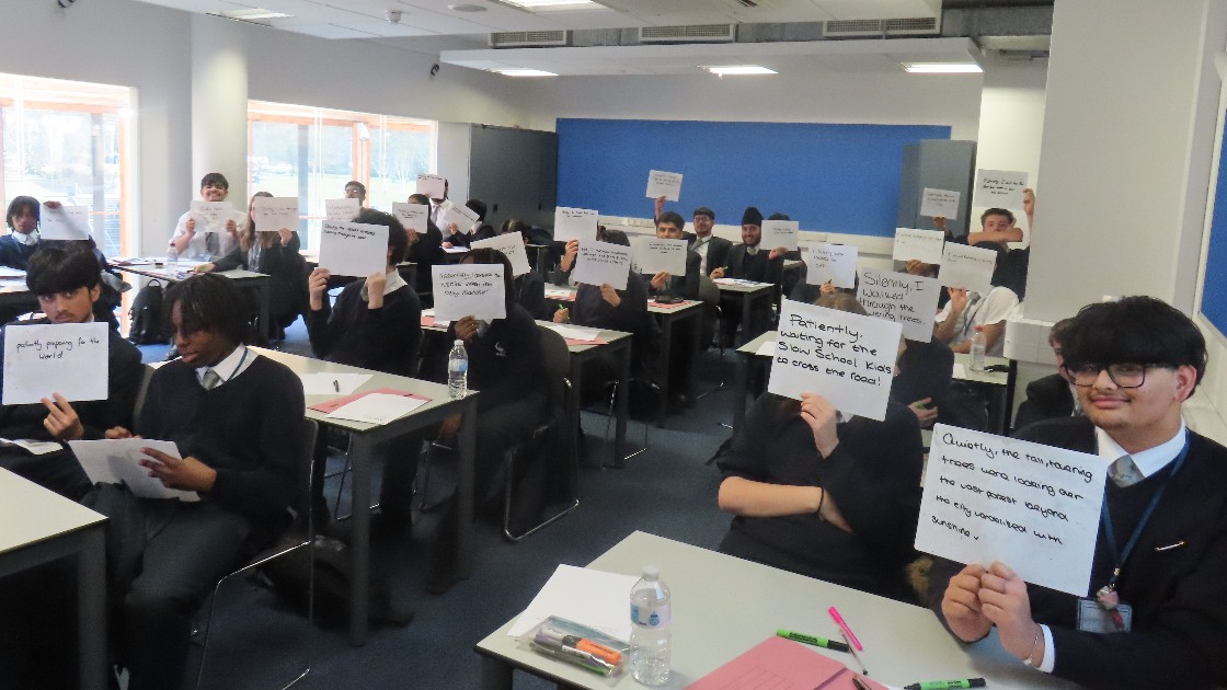Students in a classroom holding up whiteboards with written responses during an English lesson