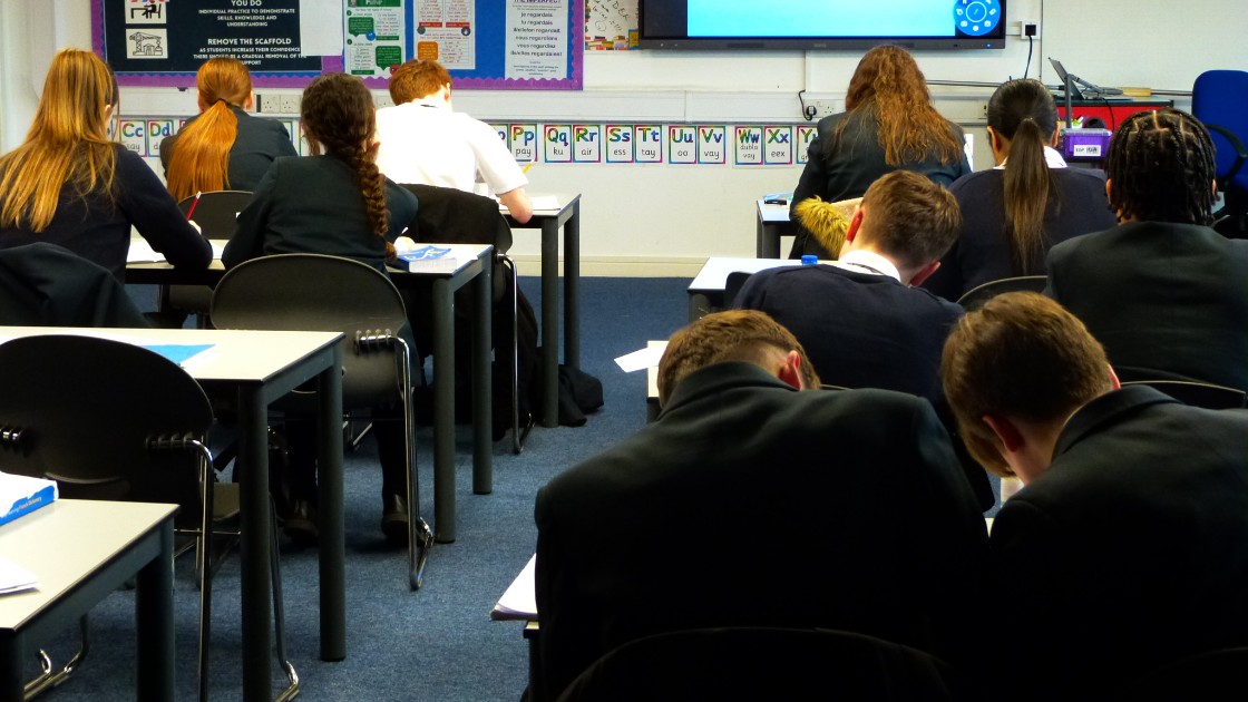 Students in a classroom sitting at desks, focusing on a lesson