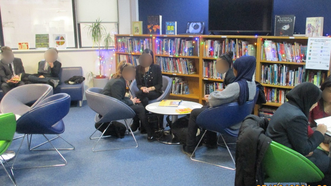 Students sitting in a library, engaged in reading and discussion