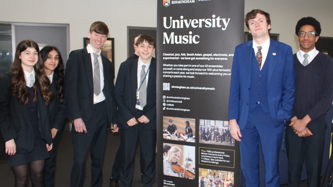Year 10 students standing next to a University Music banner