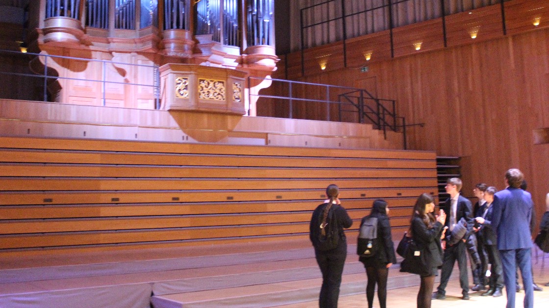 Students and a teacher in a concert hall near a large organ