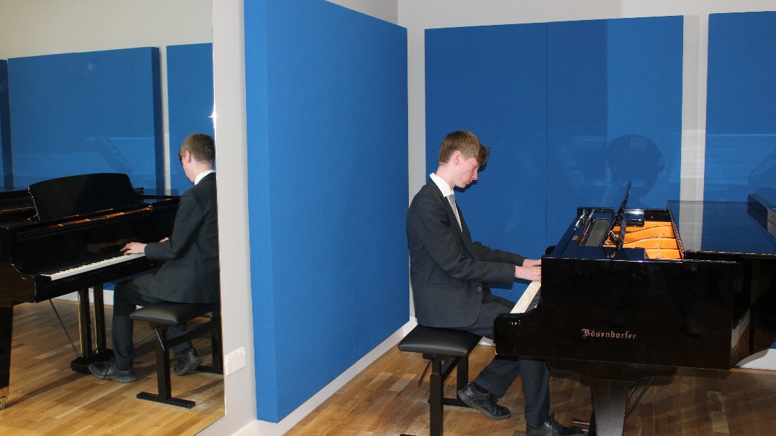 A student playing the piano in a music room