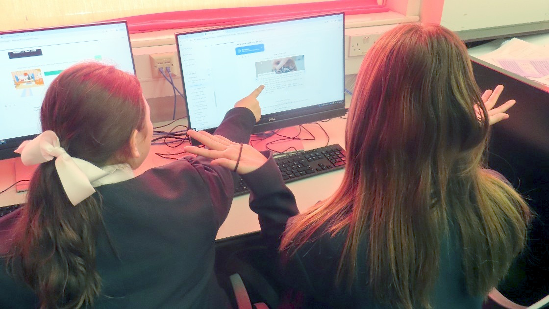 Two students working on a computer in a classroom