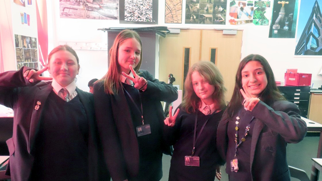 Four students posing in a classroom