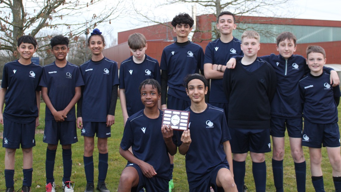 Year 8 boys football team posing outdoors with a trophy
