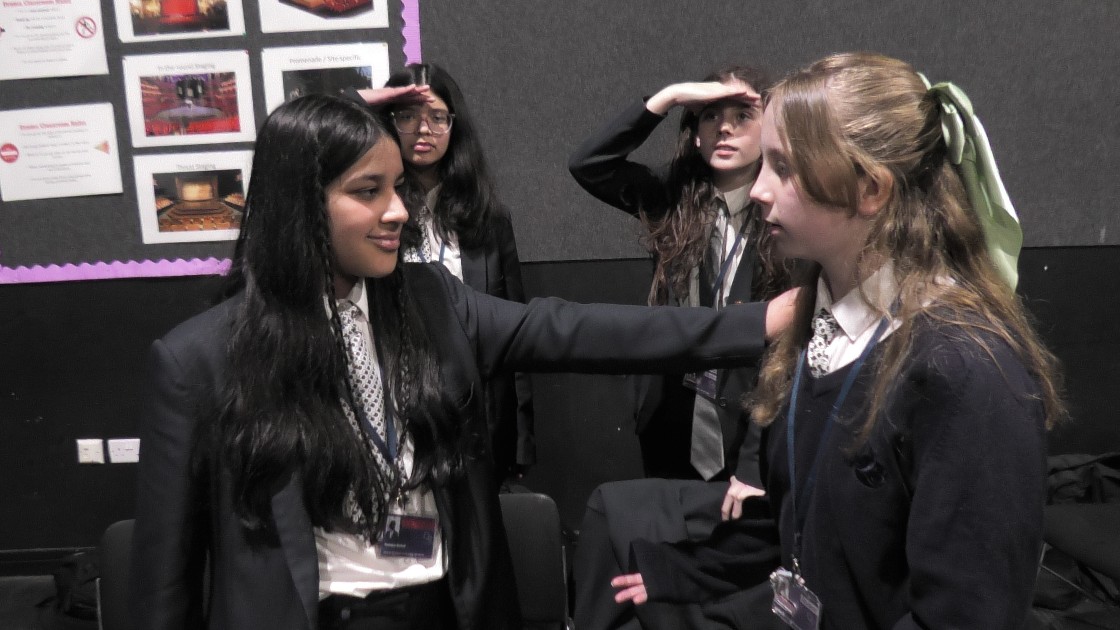 Students in a drama lesson, acting out a scene with expressive gestures
