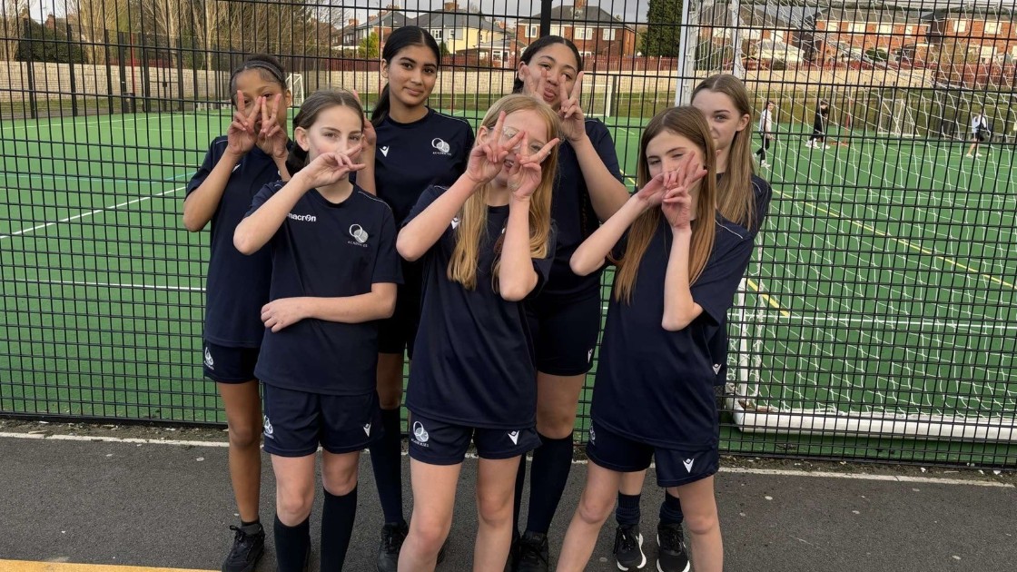 A group of Year 7-8 students in netball uniforms posing on a sports court