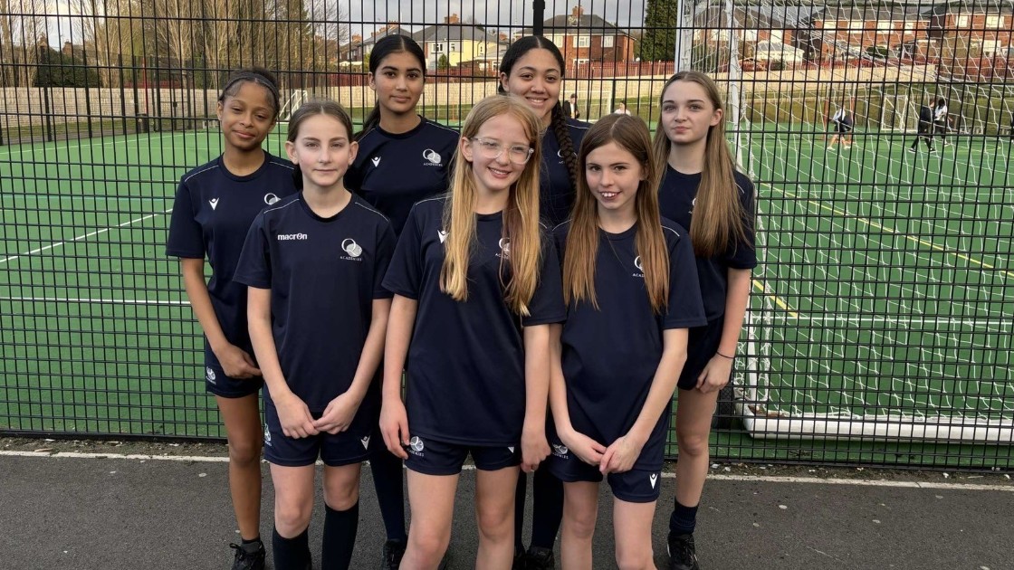 A group of Year 7-8 students in netball uniforms standing on a sports court