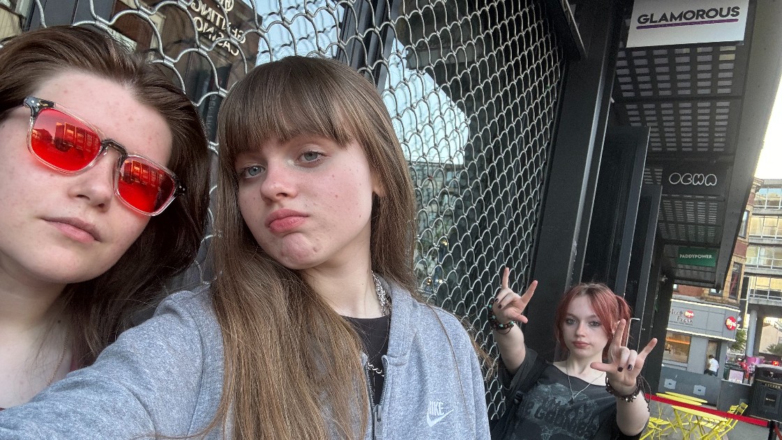 Three students outside the theatre, posing for a photo.