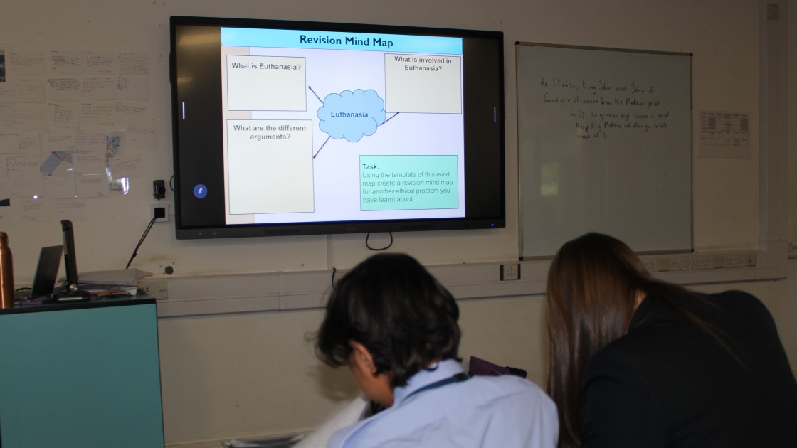 Students in a classroom looking at a mind map on euthanasia displayed on a screen during an RS lesson